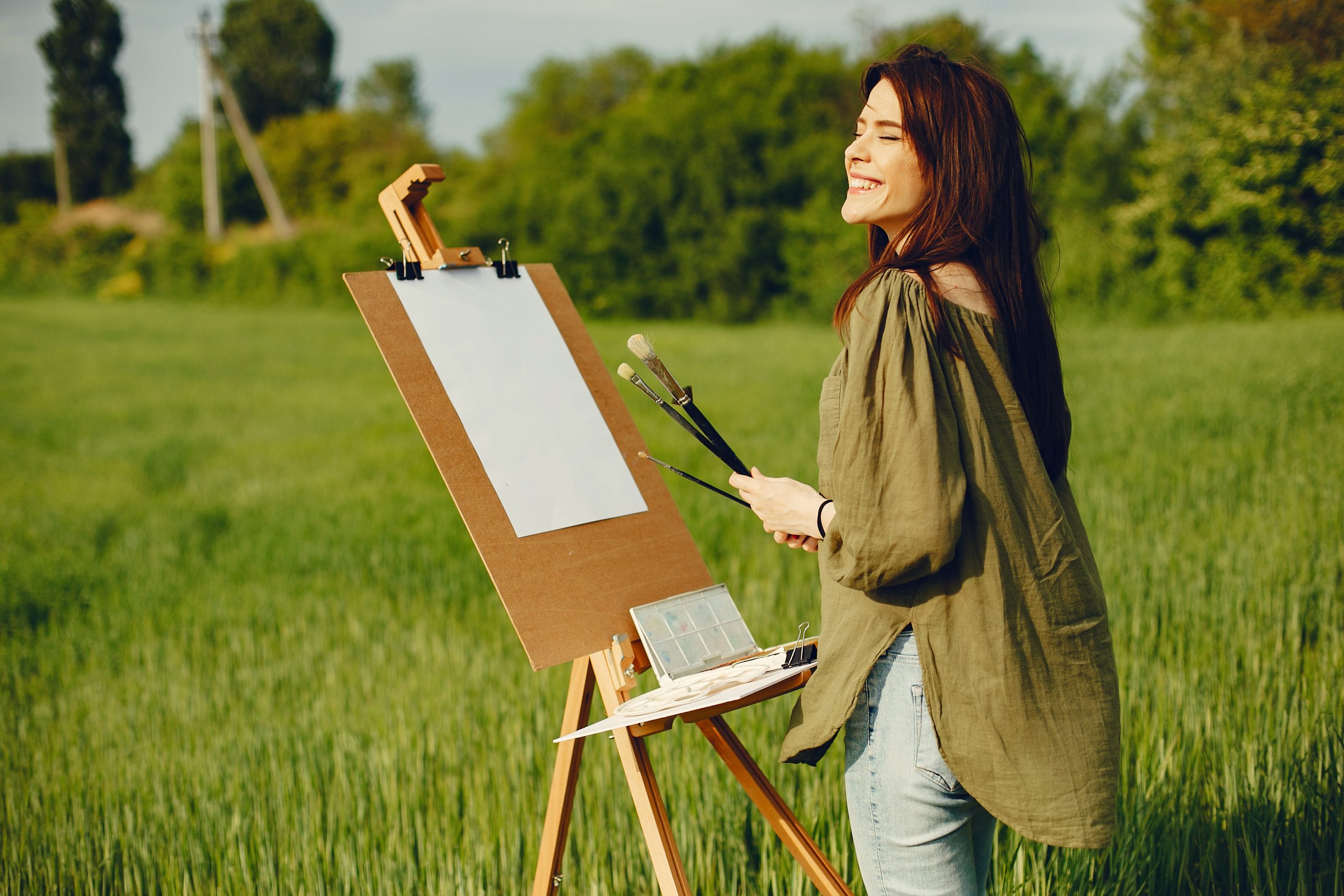 Frau stehe vor Staffelei und Leinwand und beginnt zu malen